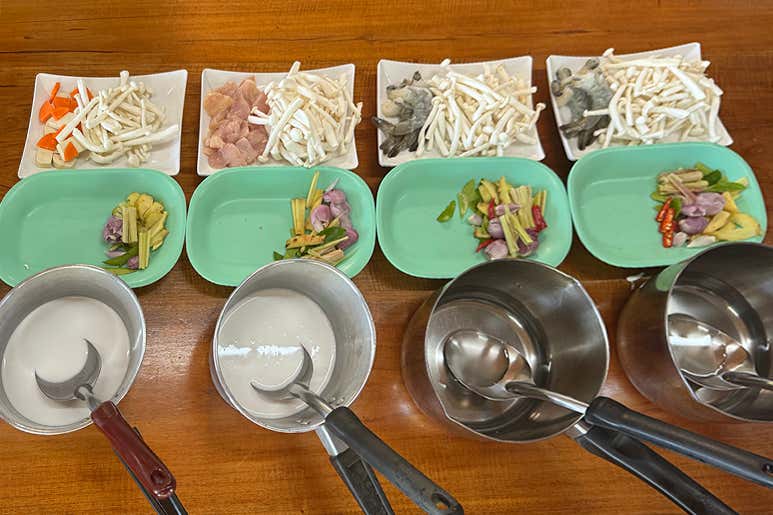 Стол, накрытый свежими продуктами — креветками и курицей с тайскими травами и овощами — во время тайского кулинарного мастер‑класса.