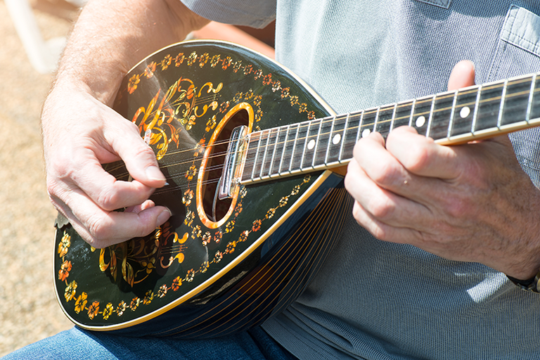 Iemand die een traditionele Griekse bouzouki met gedetailleerde patronen bespeelt