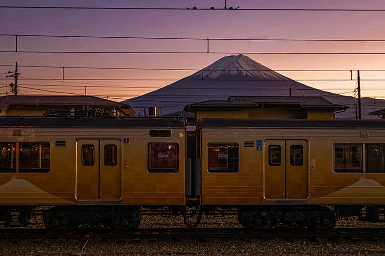 Tokaido Shinkansen train passing Mount Fuji at dusk.