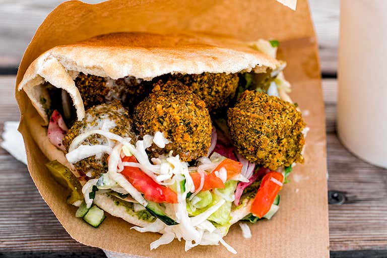 A falafel sandwich with vegetables in a pita on a wooden table