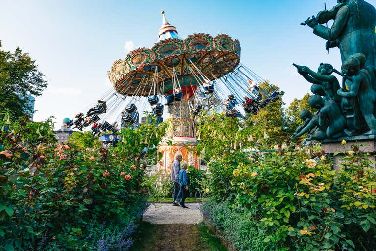 Vintage swing carousel surrounded by blooming gardens at Tivoli, Copenhagen's legendary amusement park and a bucket-list Danish attraction