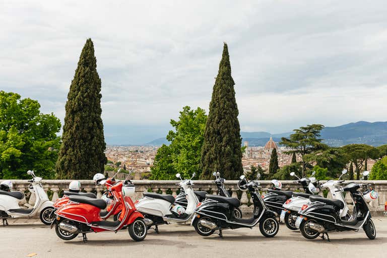 diverse Vespe parcheggiate con Firenze sullo sfondo