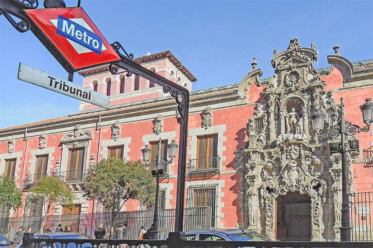 Vista da placa da estação de metrô Tribunal com um edifício histórico ao fundo em Madri.