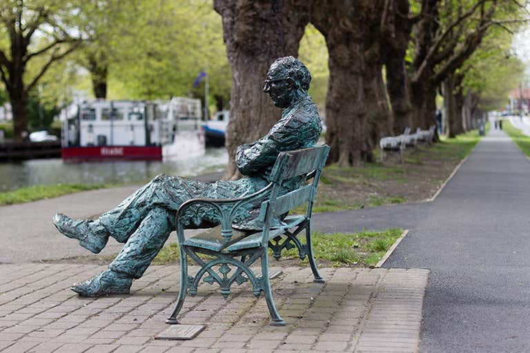 Bronze statue of poet Patrick Kavanagh seated on a bench along the Grand Canal in Dublin, Ireland.