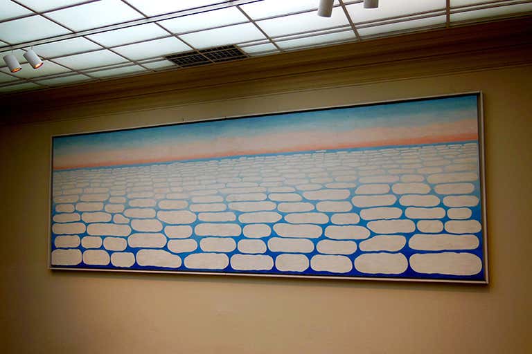 Cuadro abstracto minimalista con hileras de formas ovaladas blancas perfiladas en azul sobre un fondo claro con una línea de horizonte rosácea.