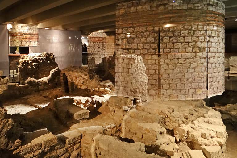 Ancient stone ruins displayed in an indoor archaeological exhibit, showcasing historical architecture and artifacts.