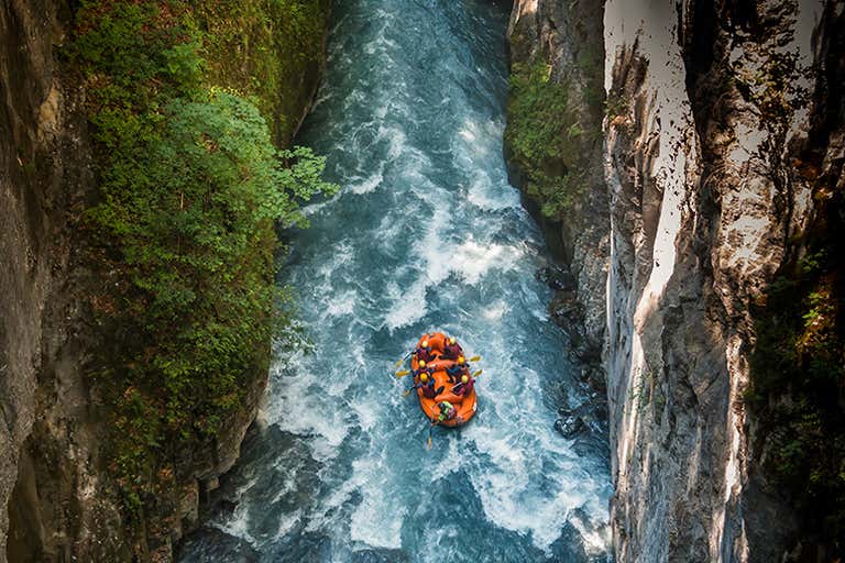 A group of people rafting surrounded by steep cliffs