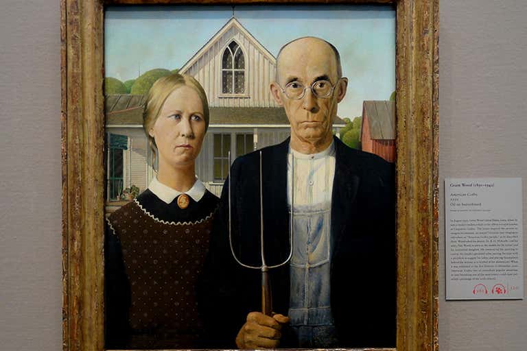 Cuadro "Gótico Americano" de Grant Wood que muestra a un granjero de rostro severo que sostiene una horca junto a una mujer, con una granja blanca al fondo.