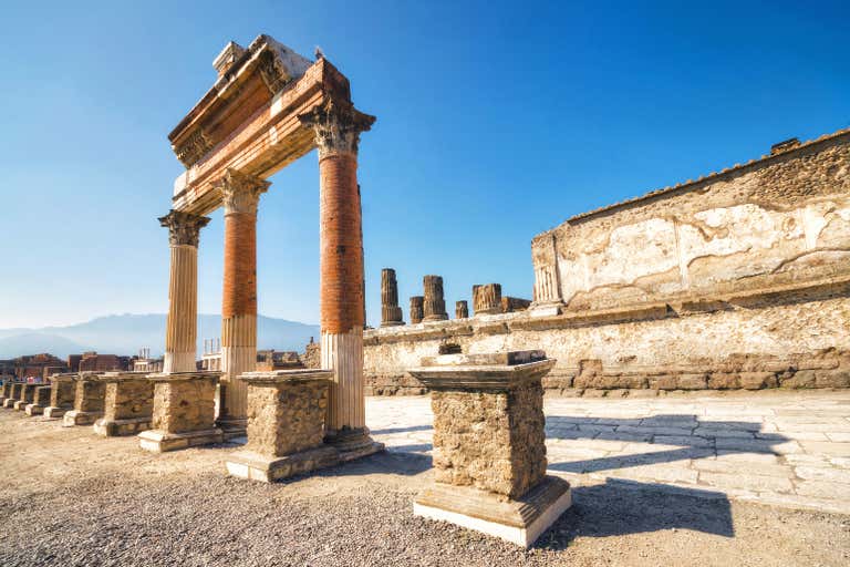 Antike römische Säulen und Ruinen vor blauem Himmel in der Ausgrabungsstätte von Pompeji, einem historischen Wunder in Italien, das man gesehen haben muss