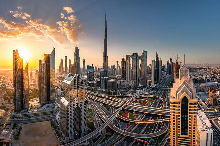 Een panoramisch uitzicht op de skyline van Dubai met de Burj Khalifa bij zonsondergang.