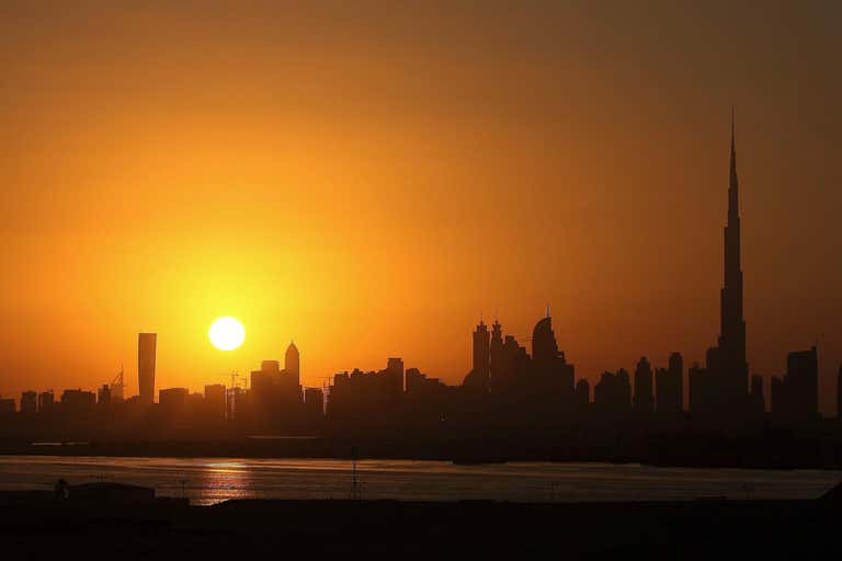 A sunrise over the Dubai skyline with the Burj Khalifa visible.