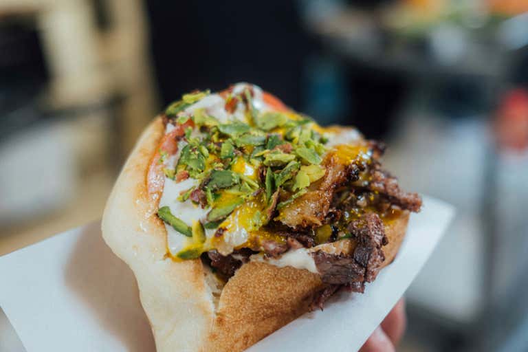 Close-up of a shawarma topped with sauce and chopped herbs.