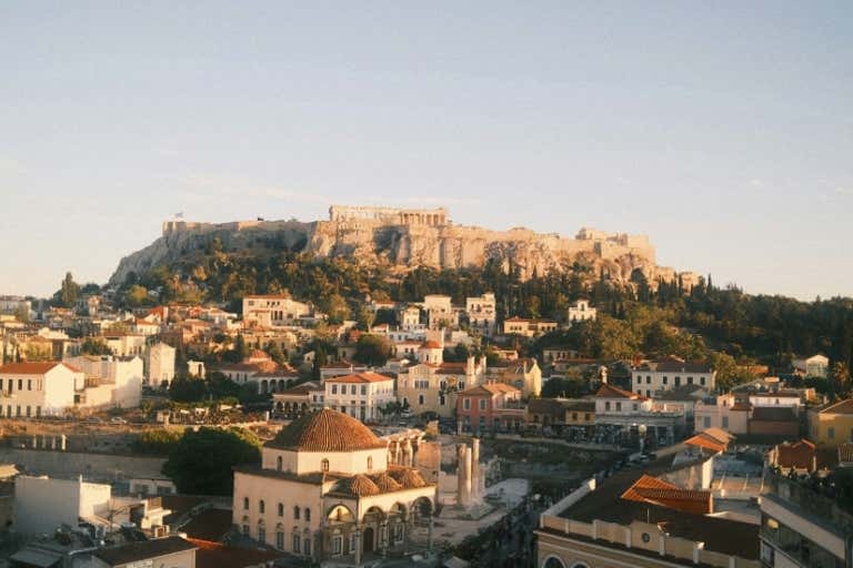 View of the Acropolis in Athens during sunrise with surrounding buildings.