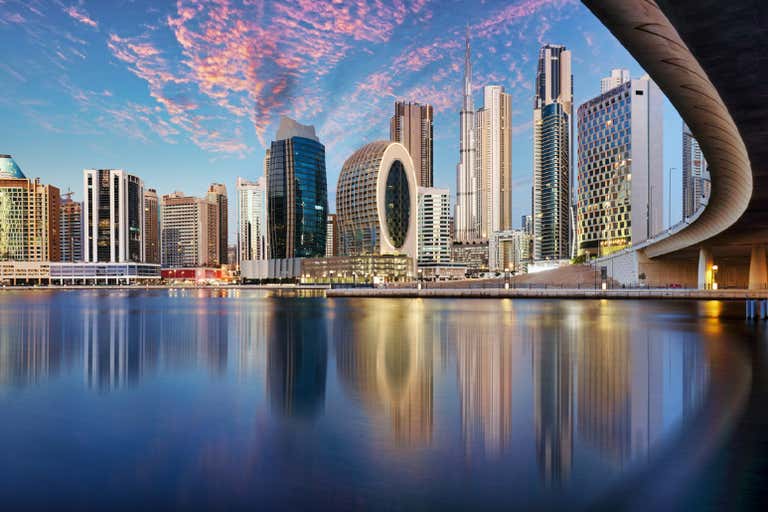 Dubai Creek with traditional wooden boats and modern buildings in the background.