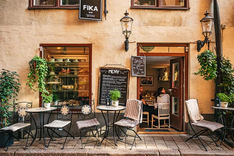 Um café aconchegante com assentos ao ar livre em Estocolmo, Suécia, com um quadro de menu e plantas.