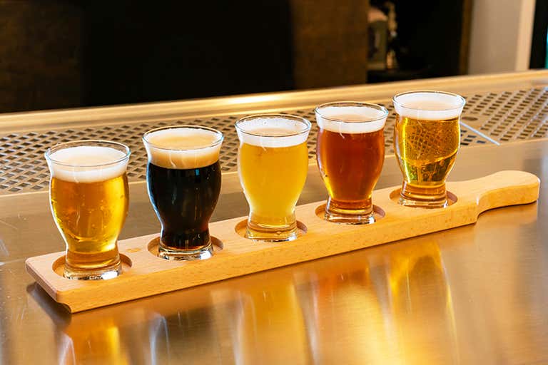 Uma seleção de cervejas artesanais variadas em uma raquete de madeira.