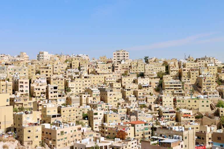 A densely packed hillside of beige buildings in Amman, Jordan.