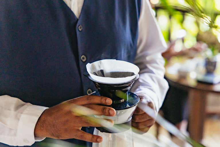 A close-up of a coffee expert holding a pour-over filter during a coffee tasting class.