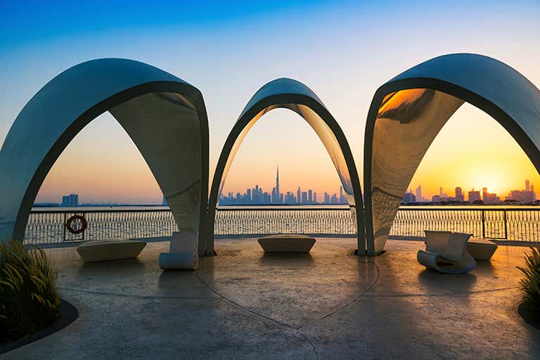 Uitzicht op de skyline van Dubai bij zonsondergang vanaf een modern architectonisch bouwwerk.
