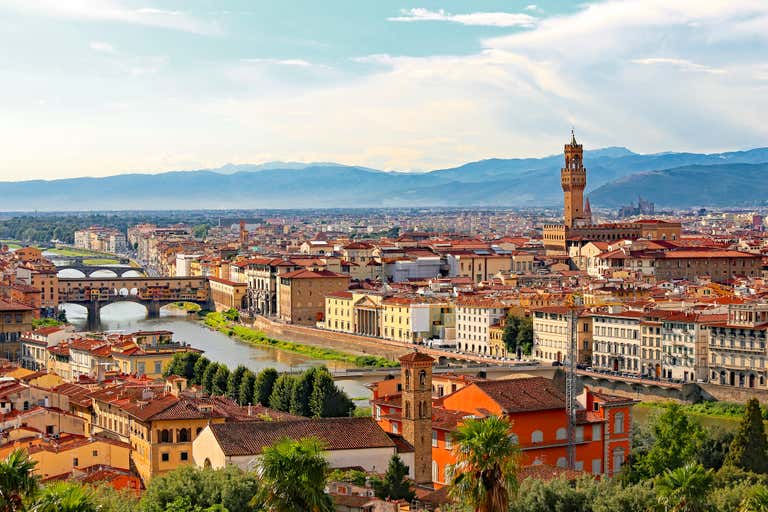 A panoramic view of Florence, Italy, with the Arno River and historic buildings.