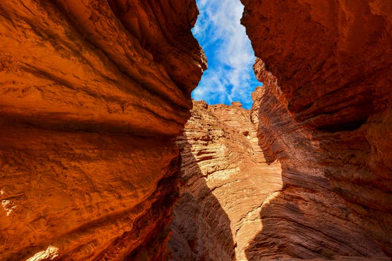 Uma vista das formações rochosas estreitas e imponentes da Quebrada de las Conchas, na Argentina, com um céu azul claro visível acima.