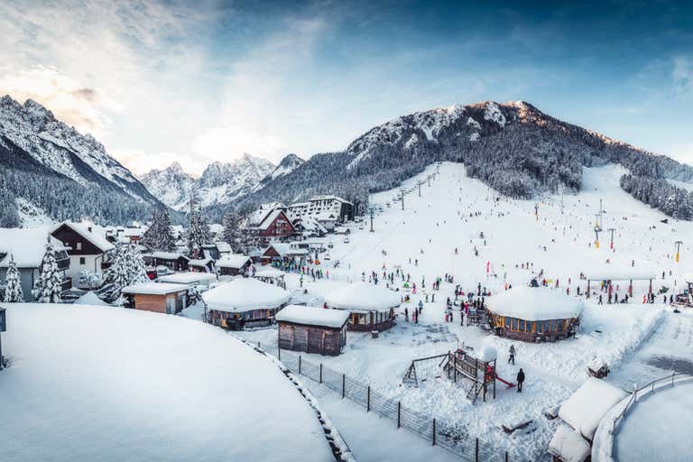 Wintery scene with log cabins nestled in Slovenia's Julian Alps and Karavanke Mountains.