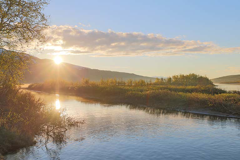Pôr do sol em um lago sereno no Parque Nacional de Abisko, Suécia.