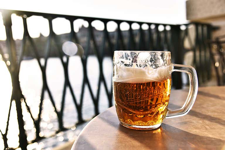 Um copo de cerveja em uma mesa à beira-mar.