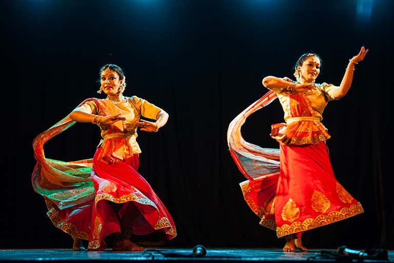Dois dançarinos se apresentam no palco com trajes tradicionais.
