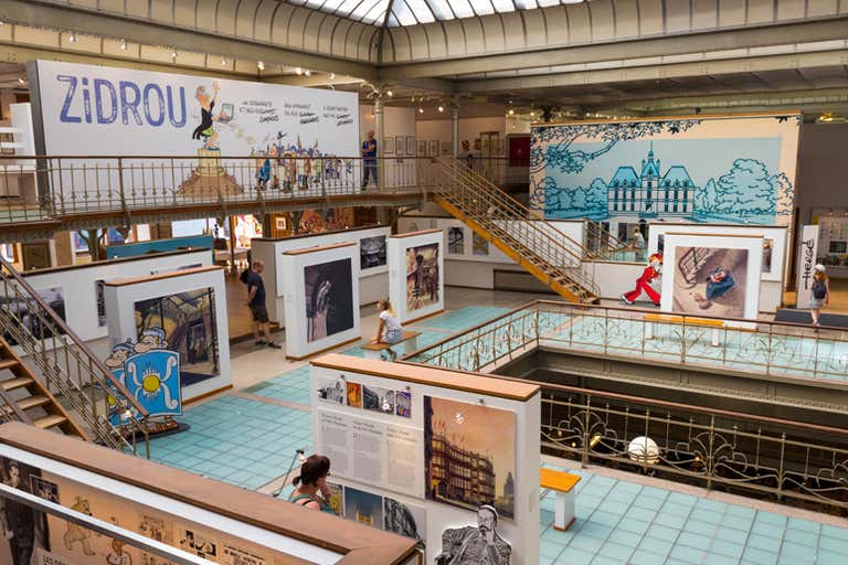 Interior view of a comic art museum with colorful displays and visitors.