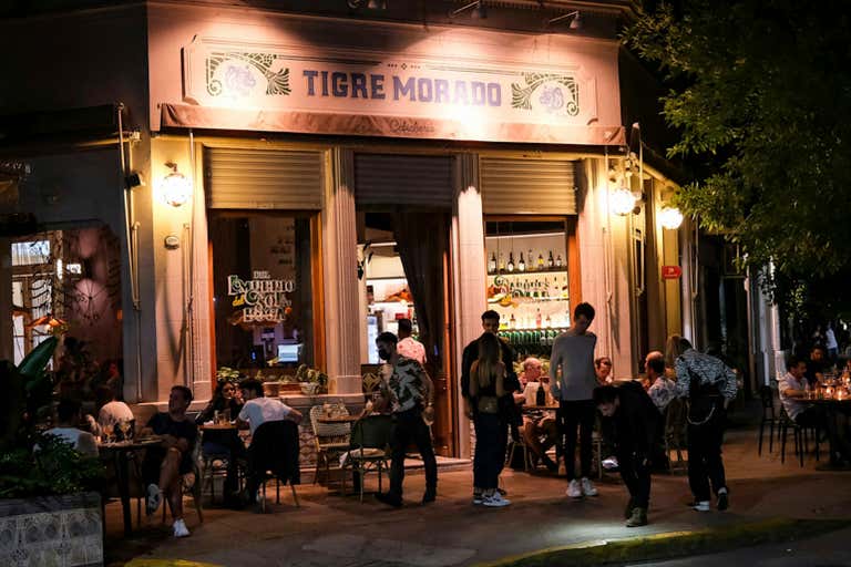 Pessoas jantando do lado de fora do restaurante Tigre Morado à noite em Buenos Aires.