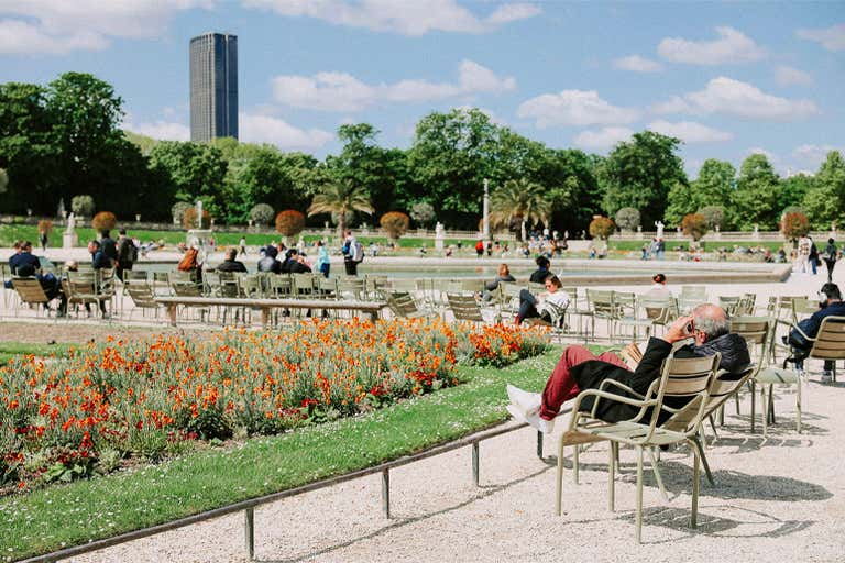 Uma vista serena dos Jardins de Luxemburgo, com vegetação exuberante e fontes.