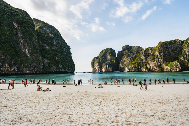 Группа туристов на пляже Майя-Бей на островах Пхи-Пхи — с бирюзовыми водами и впечатляющими скалами на заднем плане.