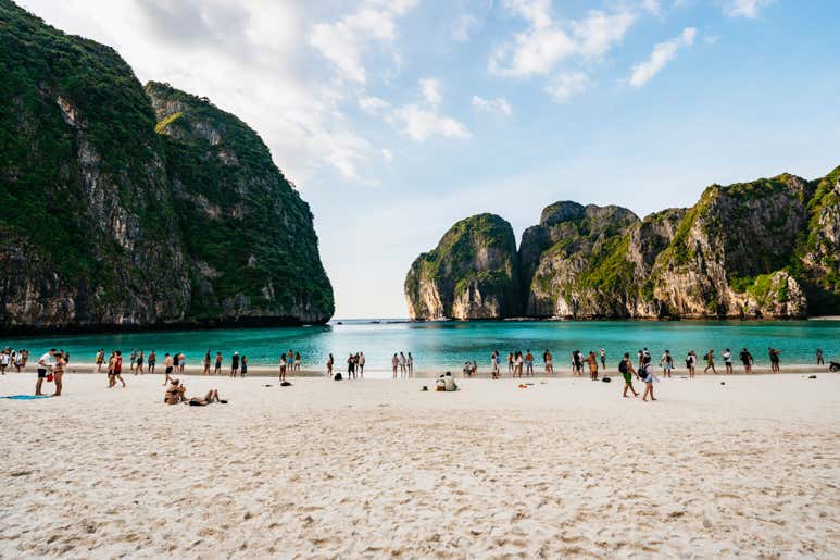 Группа туристов на пляже Майя-Бей на островах Пхи-Пхи — с бирюзовыми водами и впечатляющими скалами на заднем плане.