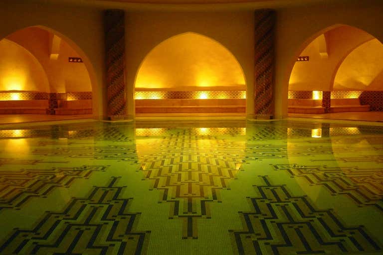 Interior cálidamente iluminado de un hammam marroquí con arquitectura tradicional y diseños estampados.