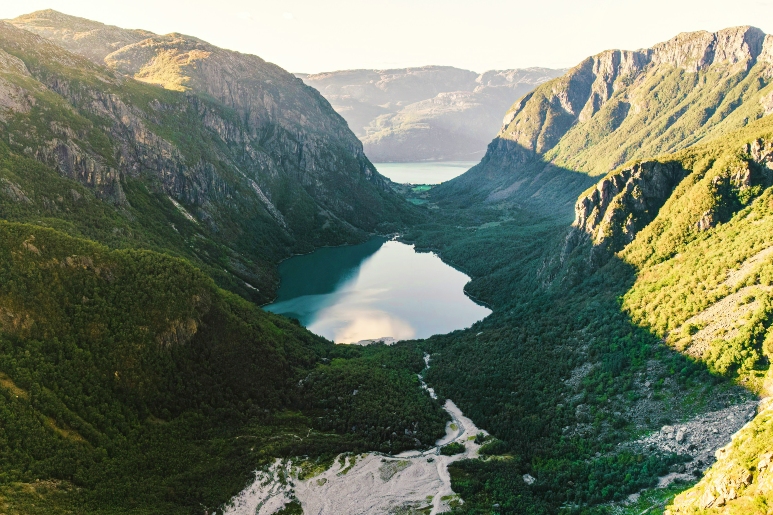 在福格勒峰國家公園（Folgefonna National Park），一片寧靜的湖泊被翠綠的山脈環抱，上方是晴朗的天空。