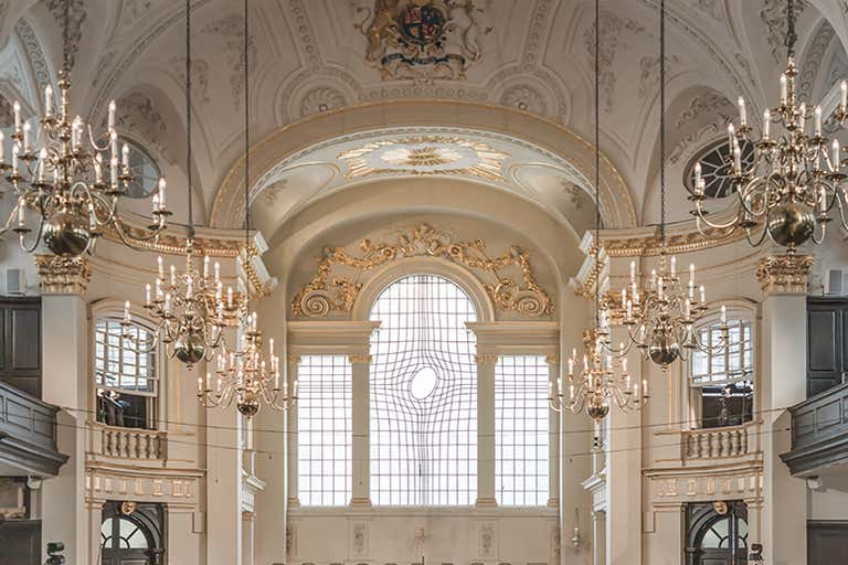 Interior of St. Martin-in-the-Fields with elegant white ceiling, gold trim, chandeliers and modern distorted glass window