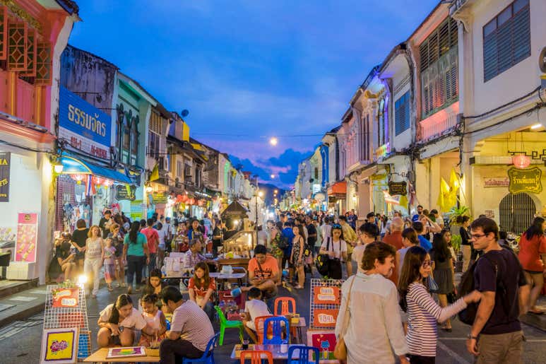 Оживлённая атмосфера рынка Нака в выходные: туристы покупают уличную еду и сувениры.