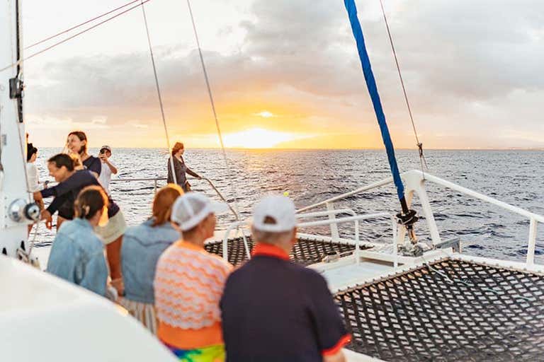 Catamaran ride at sunset with passengers enjoying the ocean near Honolulu, Hawaii.