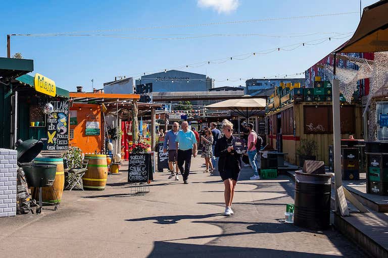 People walking through Reffen Street Food Market in Copenhagen on a sunny day.