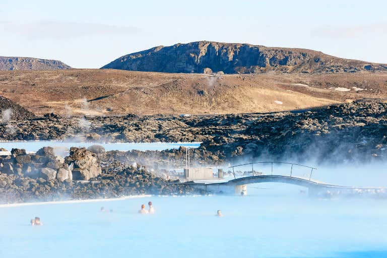 Gente relajándose en la Laguna Azul con un paisaje rocoso de fondo.