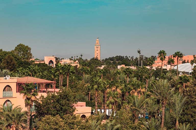 Vista de Marrakech con palmeras y la Mezquita Koutoubia al fondo.