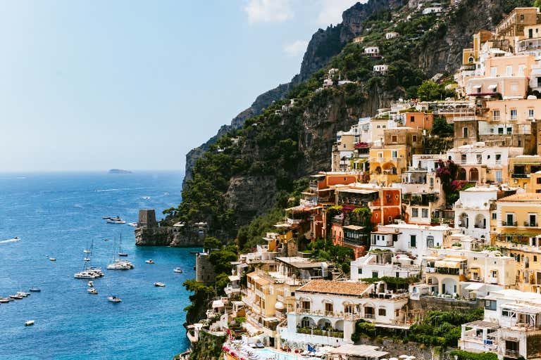 In Positano fallen bunte Häuser die Klippen hinunter zum türkisblauen Wasser des Mittelmeers und Boote säumen den Hafen.