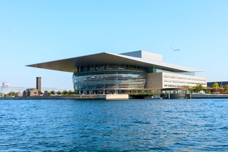 Modern Copenhagen Opera House with distinctive overhanging roof sits majestically on the waterfront, an architectural marvel in Denmark