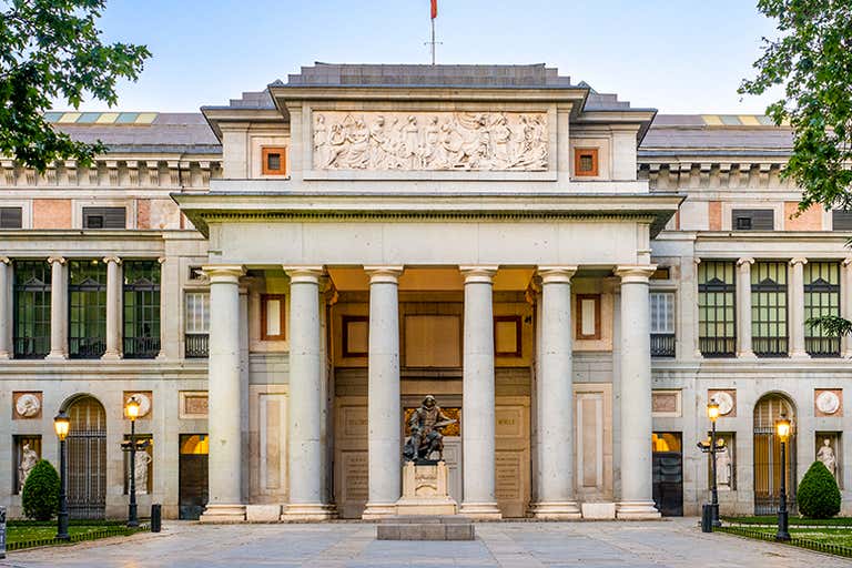 A fachada do Museu do Prado em Madri, Espanha, com colunas clássicas e uma estátua.