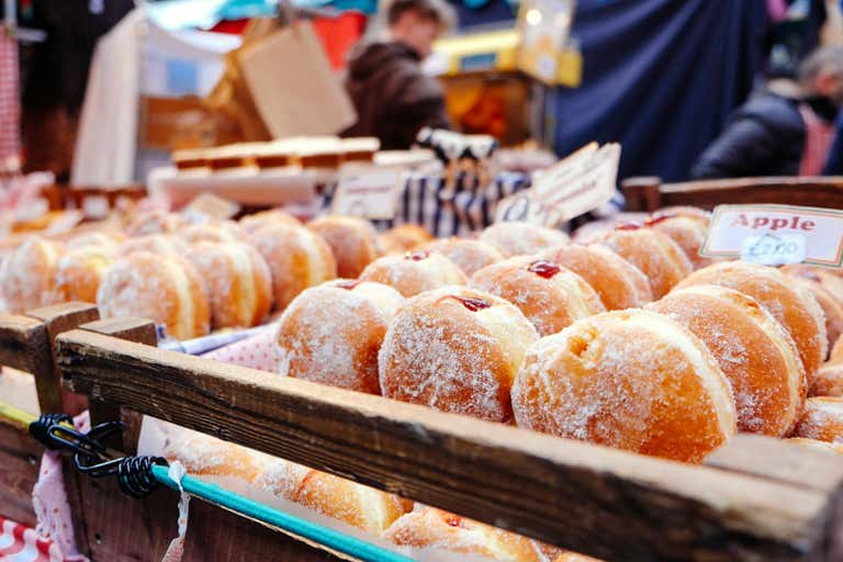 A market stall displaying trays of sugar-coated doughnuts with jam filling