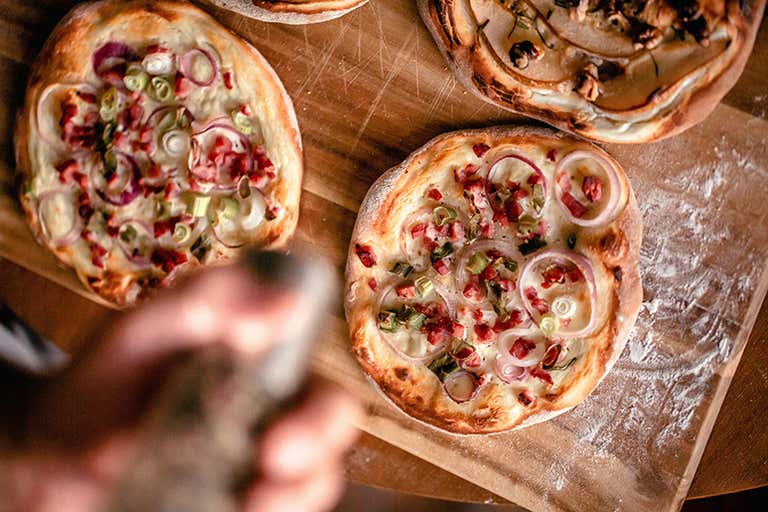 Close-up of freshly baked Flammkuchen with toppings on a wooden board