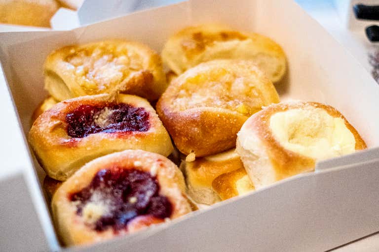 A box of assorted sweet pastries filled with fruit jams, creamy fillings, and sugar toppings.