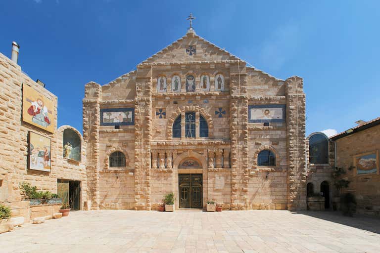 A historic stone church in Madaba with intricate mosaics on its facade.