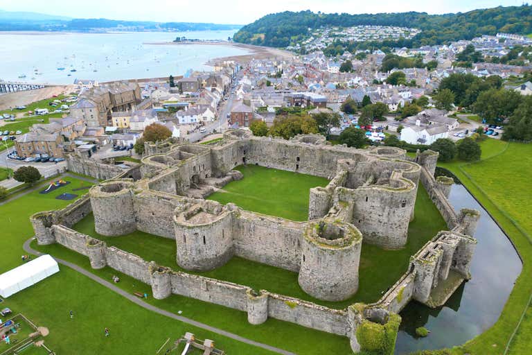 Luftaufnahme von Beaumaris Castle mit der umliegenden Stadt und der Küste.